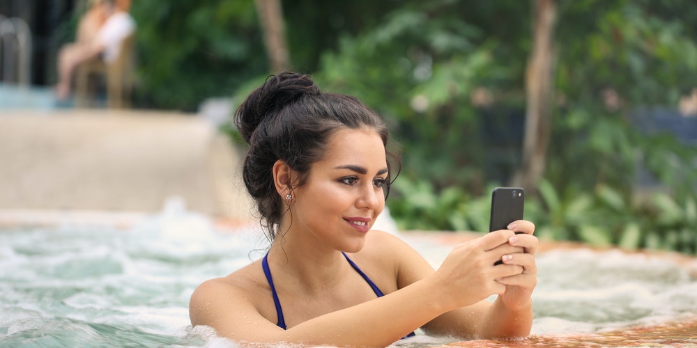 photo of a woman in jacuzzi using smartphone 3775153